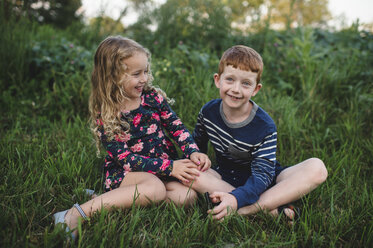 Mädchen und Bruder sitzen auf einem Feld - CUF05971