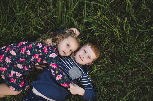 Overhead portrait of boy and sister lying on grass hugging - CUF05972