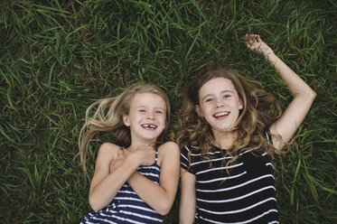 Overhead portrait of girl and her sister lying on grass - CUF05982