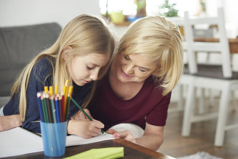 Großmutter hilft Enkelin bei den Hausaufgaben zu Hause - CUF06005
