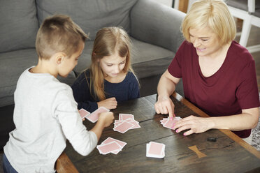 Grandmother and grandchildren playing cards at home - CUF06006