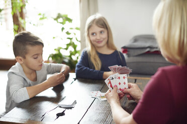Grandmother and grandchildren playing cards at home - CUF06007
