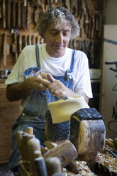 Carpenter using chisel on wooden mould for headwear in workshop - CUF06018