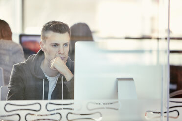 Universitätsstudent bei der Arbeit am Computer hinter einer Glaswand - CUF06069