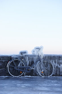 Bicycle leaning against wall, covered in ice - CUF06269