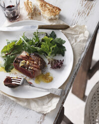 Filet Mignon mit Knoblauchbutter, gemischtem Blattsalat, Rotwein und knusprigem Brot auf einem Teller im Restaurant, Nahaufnahme - CUF06320