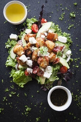Overhead view of meat and feta salad with dipping sauces on slate - CUF06328