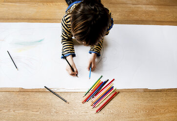 Overhead view of boy lying on floor drawing on long paper - CUF06355