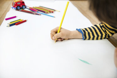 Hand eines auf dem Boden liegenden Jungen, der auf einem langen Papier zeichnet - CUF06359