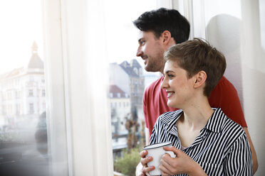 Entspanntes Paar steht am Fenster, Frau trinkt Kaffee - FKF02892
