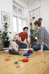 Glückliche Familie sitzt auf dem Boden und spielt mit ihrer kleinen Tochter - FKF02895