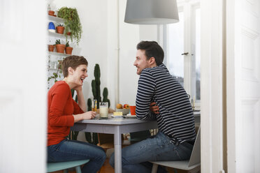 Couple sitting in kichen, talking, having breakfast - FKF02910