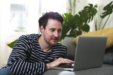 Man sitting at home, using laptop - FKF02915