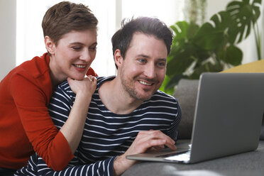 Couple sitting at home, using laptop - FKF02916