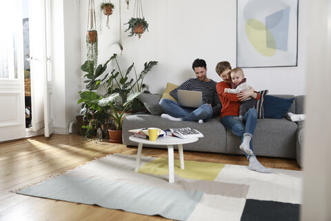 Family sitting on couch, using laptop stock photo