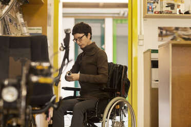 Woman in wheelchair in bicycle repair shop - CUF06401