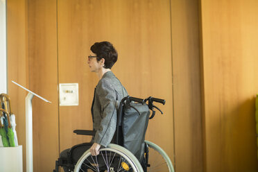 Frau im Rollstuhl, liest Schild am Büroeingang - CUF06407