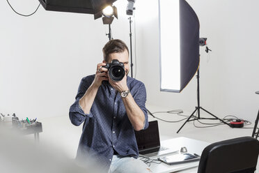 Male photographer testing focus on digital SLR in photography studio - CUF06436