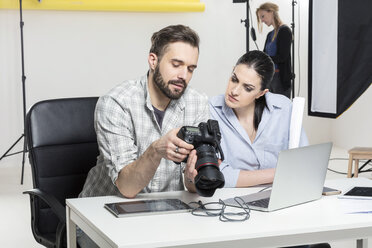 Stylist und Fotograf bei der Überprüfung von Aufnahmen mit einer digitalen Spiegelreflexkamera im Fotostudio - CUF06442