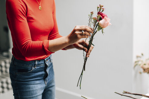 Mittelteil einer Floristin mit Schnittblumen in einer Blumenwerkstatt - CUF06467