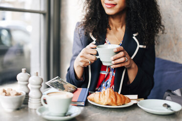 Cropped shot of woman holding coffee cup in cafe - CUF06486