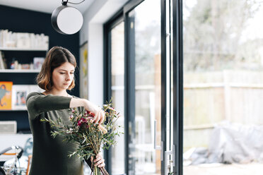 Floristikstudentin beim Arrangieren eines Blumenstraußes in einem Blumenbindeworkshop - CUF06492