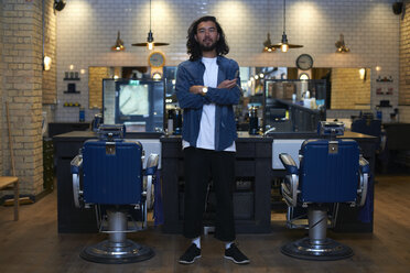 Portrait of barber with arms folded in retro style barber shop - CUF06498