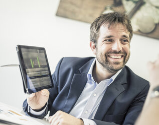 Businessmen at office desk meeting showing digital tablet - CUF06517