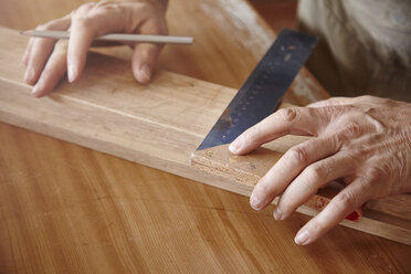 Hands of male carpenter using set square at workbench - CUF06521