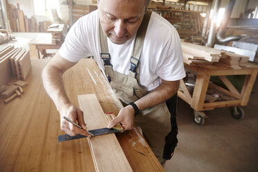 Male carpenter using set square at workbench - CUF06522