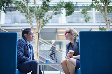 Businesswoman and man at meeting in office atrium - CUF06547