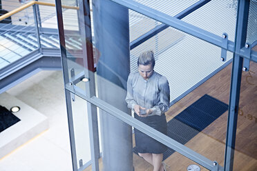 Hohe Winkel Ansicht der Geschäftsfrau Blick auf Smartphone auf Büro Treppe - CUF06557