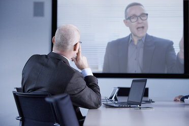 Geschäftsmann beobachtet Telefonkonferenz im Büro - CUF06558