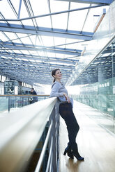 Happy businesswoman leaning against office balcony - CUF06572