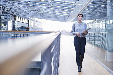 Businesswoman walking along office balcony - CUF06573