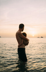 Vater und kleine Tochter beobachten gemeinsam den Sonnenuntergang am Meer - GEMF01976