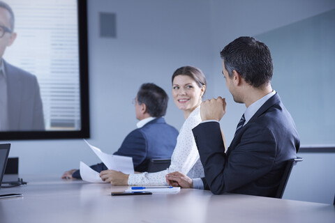 Geschäftsfrau schaut während einer Telefonkonferenz im Büro über ihre Schulter, lizenzfreies Stockfoto