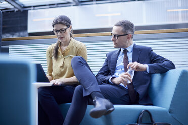 Businessman and woman looking at laptop in office meeting - CUF06636