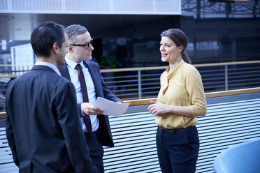 Geschäftsfrau und Männer mit Papierkram im Atrium eines Büros - CUF06641