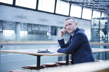 Portrait of businessman sitting at office balcony table - CUF06646