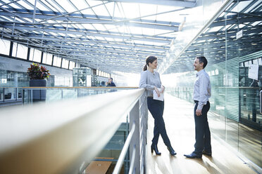 Businessman and woman talking on office balcony - CUF06647