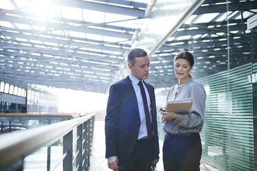 Businesswoman and man reading paperwork on office balcony - CUF06651