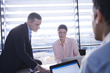 Businessmen and woman having meeting at office desk - CUF06659