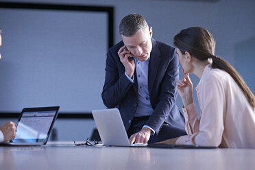 Business team making smartphone call and using laptop on office desk - CUF06662