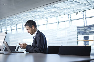 Geschäftsmann schaut auf Smartphone am Konferenztisch - CUF06668