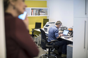 Mann sitzt am Schreibtisch im Büro und benutzt einen Laptop - CUF06679