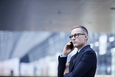 Gestresster Geschäftsmann telefoniert mit seinem Smartphone im Atrium seines Büros - CUF06702