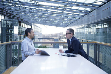 Two businessmen meeting at office balcony table - CUF06710