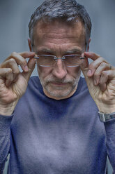 Porträt eines ergrauten reifen Mannes, der seine Brille abnimmt - CUF06728