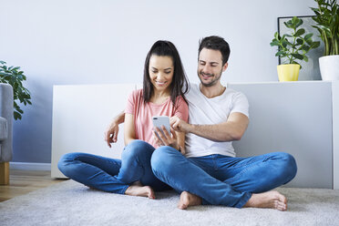 Couple sitting on floor and using smartphone - BSZF00395
